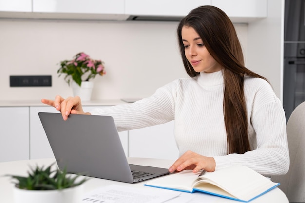 Slimme mooie jonge vrouw opent laptop om thuis online te studeren