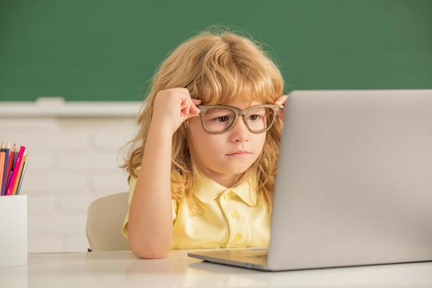 Slimme nerd jongen in glazen met laptop. 1 september e-learning. kind studeert op de computer. tiener jongen in de klas. terug naar school. kennis dag. concept van online onderwijs.