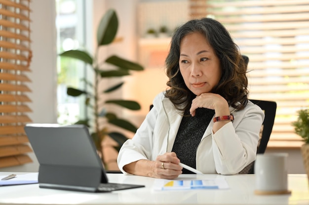 Slimme professionele senior zakenvrouw kijken naar zakelijke training online webinar op laptopcomputer op afstand werken vanuit huis