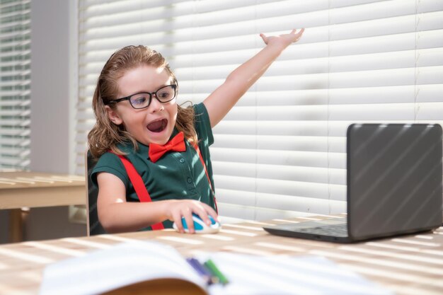 Slimme schooljongen die thuis huiswerk schrijft kleine student met notebookcomputer klaar om school te studeren...