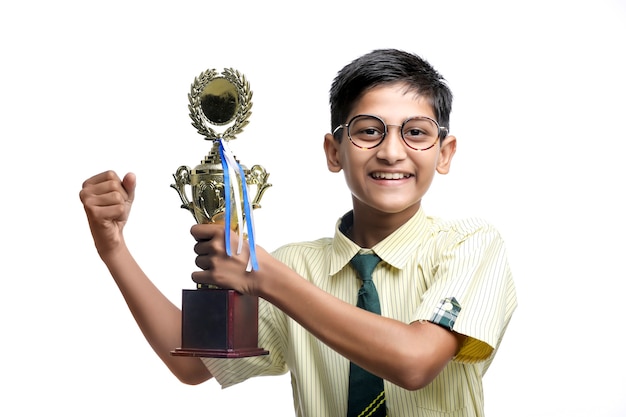 Slimme schooljongen die zijn trofee opheft als winnaar in de schoolcompetitie.