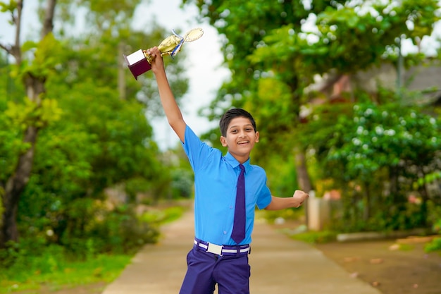 Slimme schooljongen die zijn trofee opheft als winnaar in de schoolcompetitie.