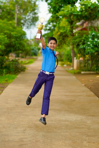 Slimme schooljongen die zijn trofee opheft als winnaar in de schoolcompetitie.