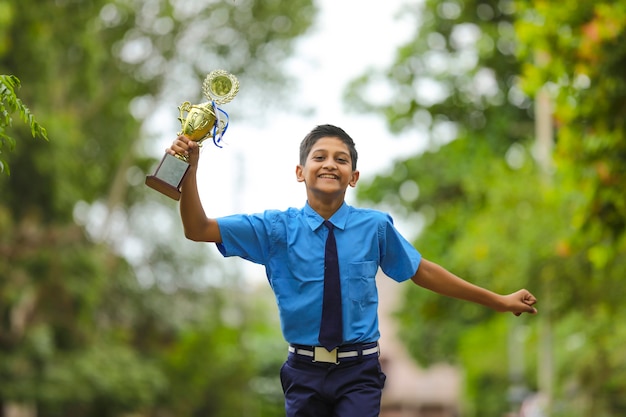 Slimme schooljongen die zijn trofee opheft als winnaar in de schoolcompetitie.