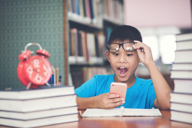 Slimme schooljongen huiswerk met telefoon