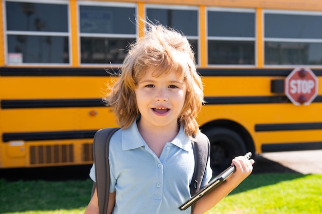 Foto slimme schooljongen met digitale tablet op schoolpark in de buurt van schoolbusonderwijs en leren voor kinderen