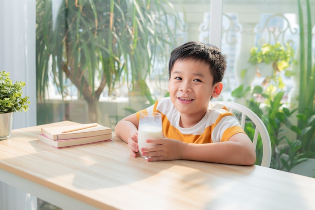 Slimme schooljongen zit aan de tafel met veel boeken Concept van onderwijs.