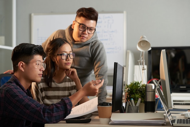 Slimme serieuze informaticastudenten verzamelden zich op het computerscherm om software-arch...