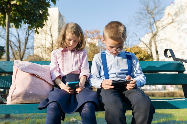 Slimme serieuze kinderen jongen en meisje zijn op zoek naar smartphones