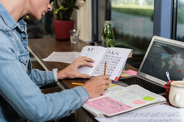 Slimme student. aangename jongeman die zijn huiswerk doet terwijl hij in het boek kijkt