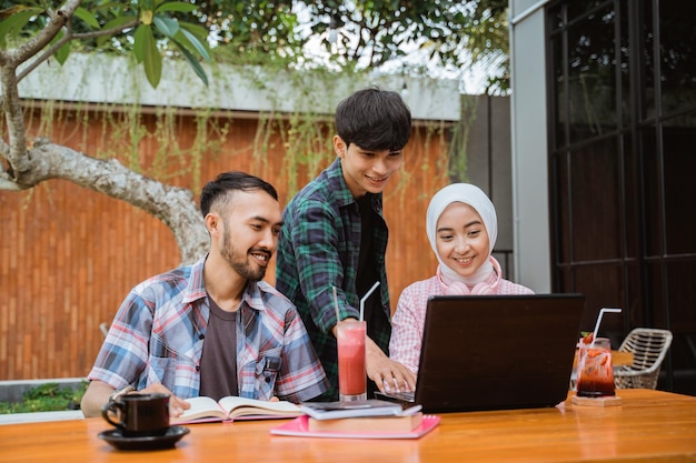 Slimme studenten studeren samen met een laptop en boeken op terras