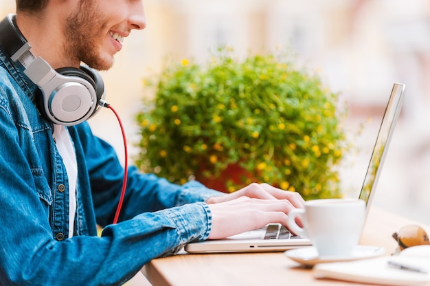 Slimme technologie voor een perfecte stijl. Bijgesneden afbeelding van lachende jonge man aan het werk op laptop