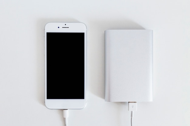 Foto slimme telefoon aangesloten op power bank-oplader over de witte achtergrond