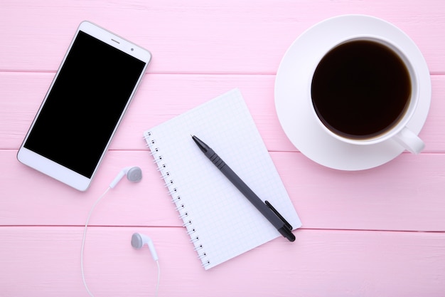 Slimme telefoon met laptop en kopje koffie op roze houten achtergrond