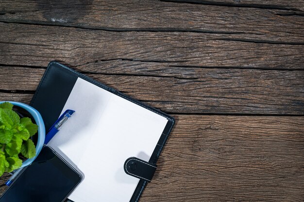 Foto slimme telefoon pen kladblok geplaatst op een houten tafelblad-weergave