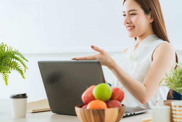 Slimme uitvoerende aziatische vrouw witte jurk ontmoeting met collega met laptop presentatie kantoor achtergrond