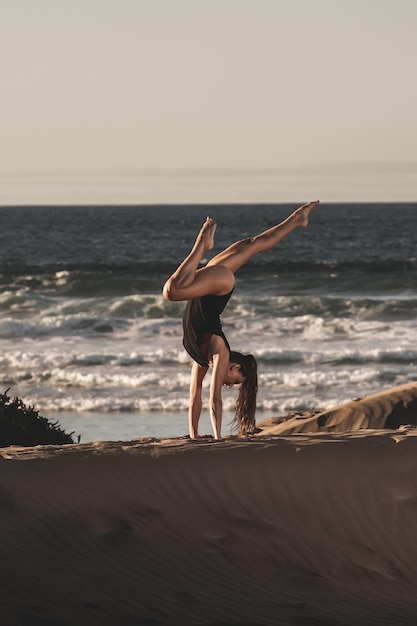 Slimme vrouw doet yoga op het strand.