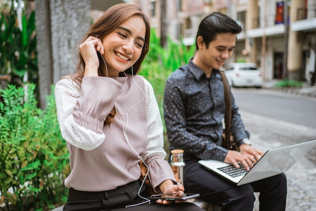 Slimme vrouw zittend op een bankje in het park luisteren naar muziek