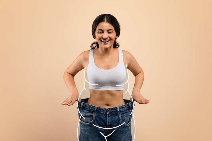 Photo slimming concept slim indian woman wearing oversized jeans posing on beige background