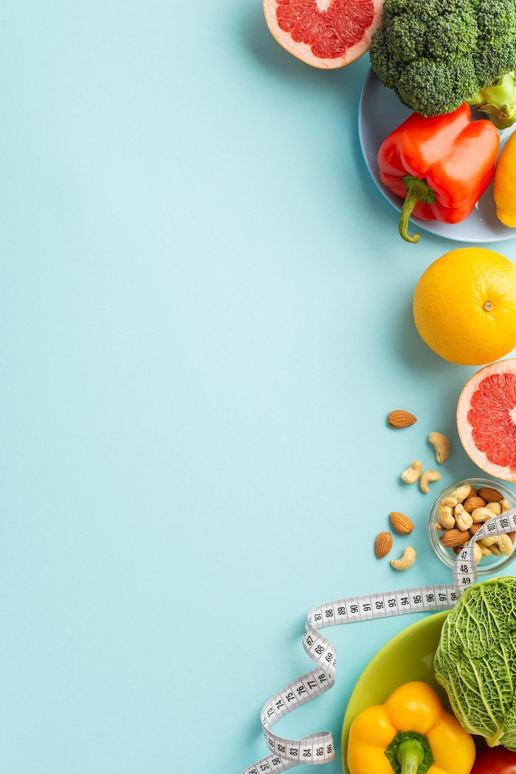 Photo slimming concept top view vertical photo of plates with fruits and vegetables cabbage pepper cauliflower grapefruit almonds cashew and tape measure on isolated pastel blue background with copyspace