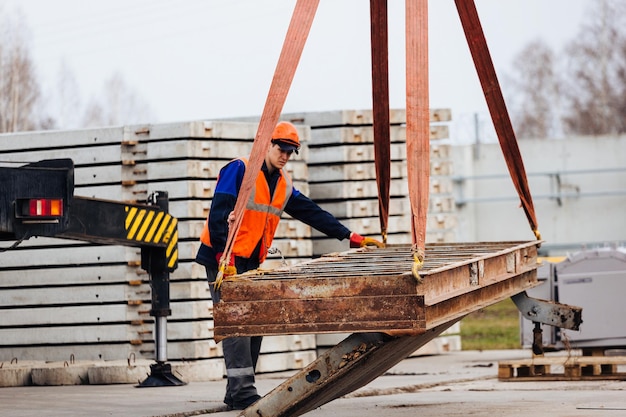 L'imbracatura in casco e giubbotto controlla lo scarico delle strutture metalliche in cantiere