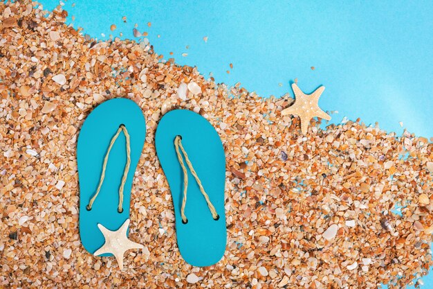 Slippers en strandzand op blauwe achtergrond