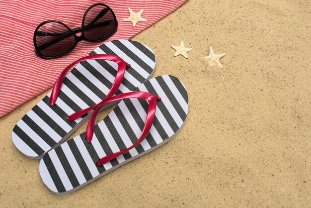 Slippers en zonnebril in het zand Zomervakantie concept Kopieer de ruimte