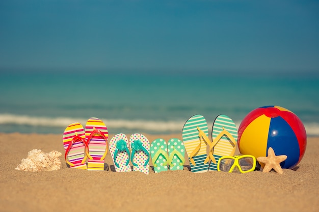 Slippers op zandstrand tegen blauwe zee en lucht and