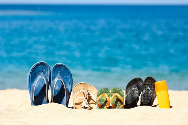 여행하는 동안 자연의 바다 모래에 온 가족 슬리퍼 신발과 함께 휴가에 물가에서 휴식