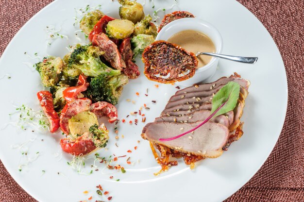 Slised meat meal with vegetables on white plate