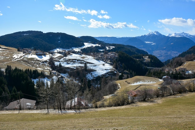 Foto pendii di piccole montagne con case situate su di essi paesaggio pittoresco invernale con cielo luminoso