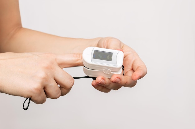 Sloseup of a woman's hands measuring pulse and saturation with a pulse oximeter device