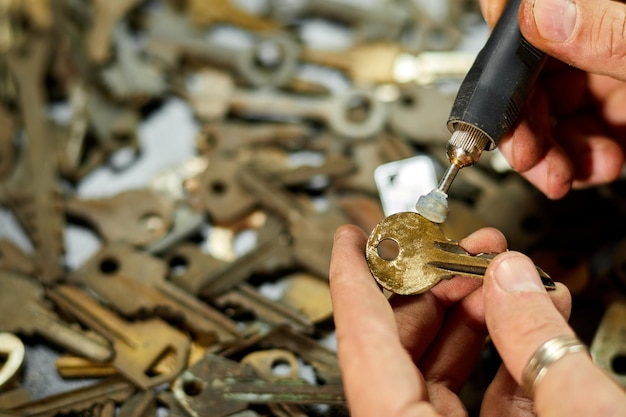 Slotenmaker in werkplaats maakt nieuwe sleutel gebruik slijpmachine productie van dubbele metalen sleutel