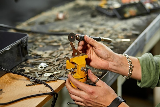 Slotenmaker in werkplaats maakt nieuwe sleutel gebruik slijpmachine productie van dubbele metalen sleutel