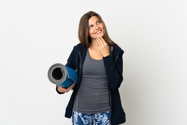 Slovak girl going to yoga classes isolated on white background looking up while smiling