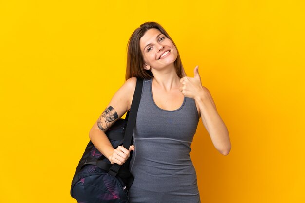 Slovak sport woman with sport bag isolated on yellow background with thumbs up because something good has happened