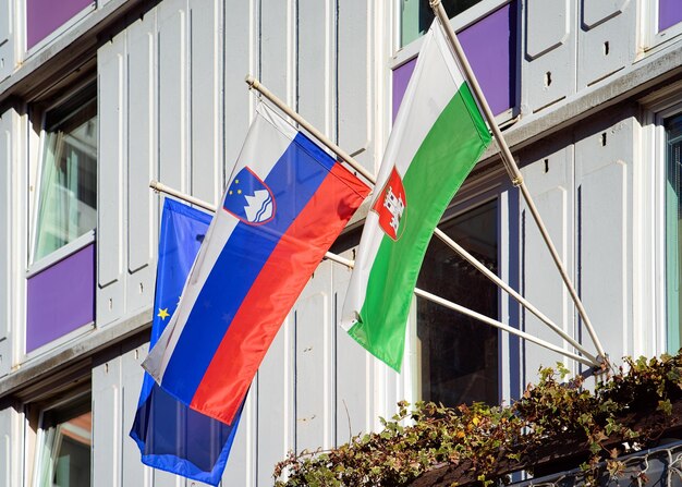 Sloveense vlag, Ljubljana-vlag en EU-vlag bij het inbouwen in de oude stadsstraten van Ljubljana, Slovenië in de avond. Sloveens uitzicht op de stad in het voorjaar. Oriëntatiepunt. Stedelijke groene hoofdstad.