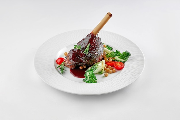 Slow cooked lamb Shank in wine sauce on a white plate on a white tablecloth