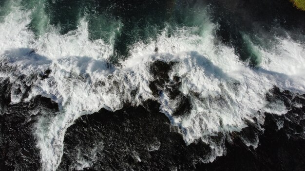 A slow motion shot of waves crashing into a black rock