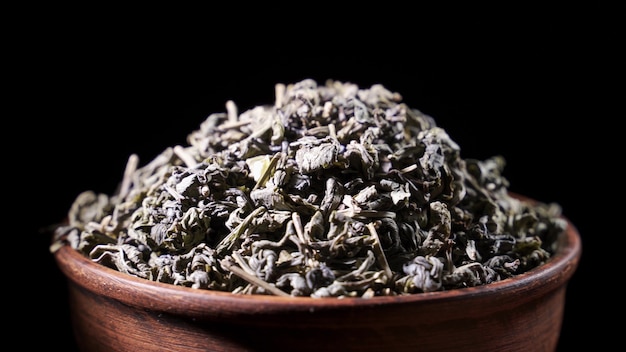 SLOW MOTION: Tea leaves fall on a pile of a green tea - Macro shot.