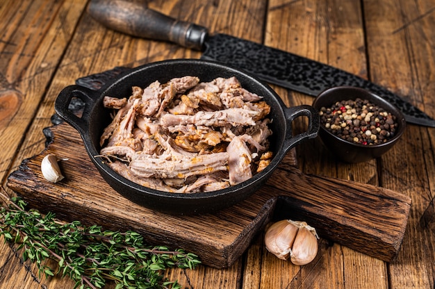 Slow shredded  puilled pork meat in a pan with butcher knife