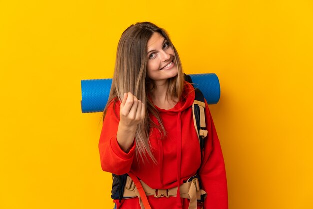 Slowaakse bergbeklimmer vrouw met een grote rugzak geïsoleerd op gele achtergrond geld gebaar maken