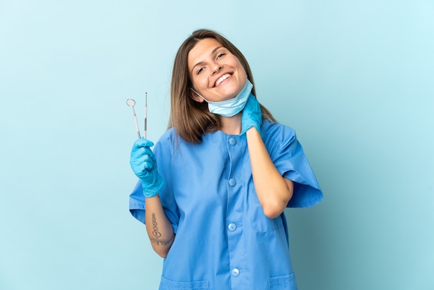 Slowaakse tandarts met tools geïsoleerd op blauwe achtergrond lachen