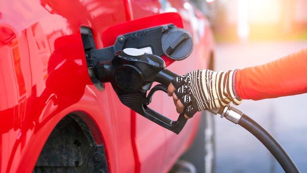 Sluit de hand van de werknemer met het mondstuk voor het vullen van dieselbrandstof in de rode pick-up auto bij het tankstation