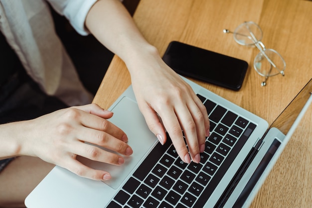 Sluit freelancervrouw omhoog gebruikend computer en thuis werkend aan project