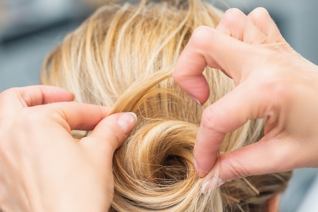 Sluit omhoog achtermening die van kapper kapsel voor lang haar van blondevrouw maken.