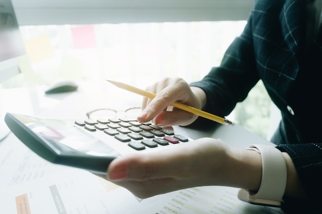 Sluit omhoog Bedrijfsvrouw die calculator gebruiken voor wiskundefinanciën op houten bureau in bureau