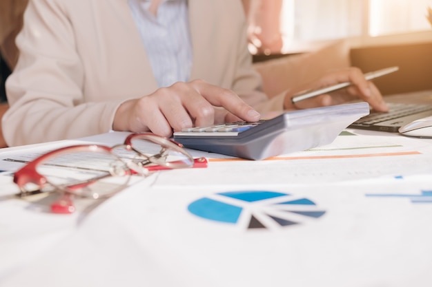 Sluit omhoog Bedrijfsvrouw gebruikend calculator en laptop voor wiskundig financiën op houten bureau in bureau