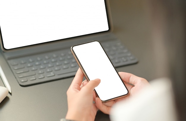 Sluit omhoog beeld van de hand van een onderneemster gebruikt een lege het schermsmartphone met laptop.