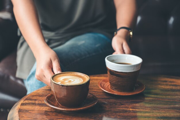 Sluit omhoog beeld van een vrouw die en twee koffiekop in het koffie houden dienen